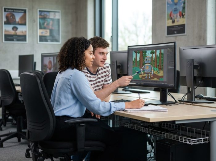 Deux étudiants collaborant sur un projet d'animation 3D dans un laboratoire informatique universitaire